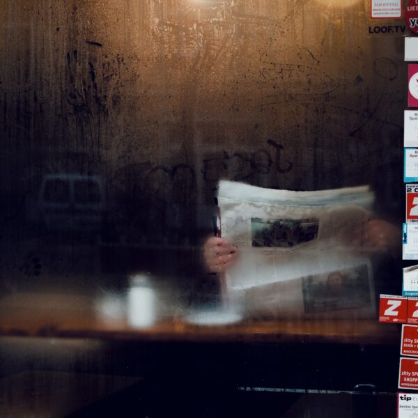 Person reading newspaper behind cafe window