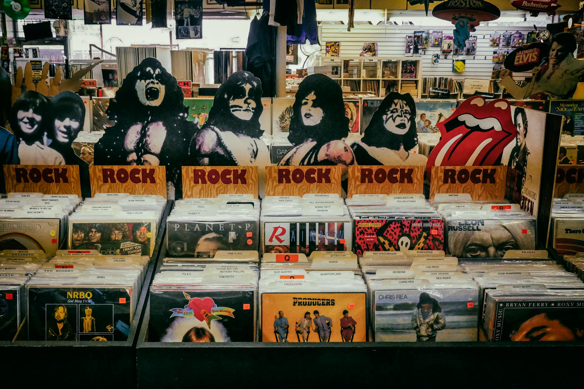 A shelf of rock music vinyl records and images of the bandmembers of Kiss at a music store