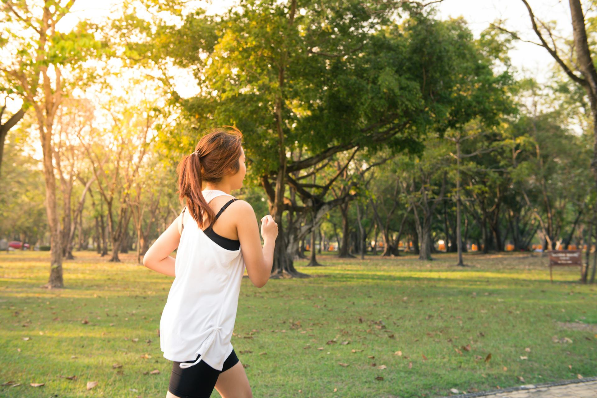 A woman in a while shirt running through a park